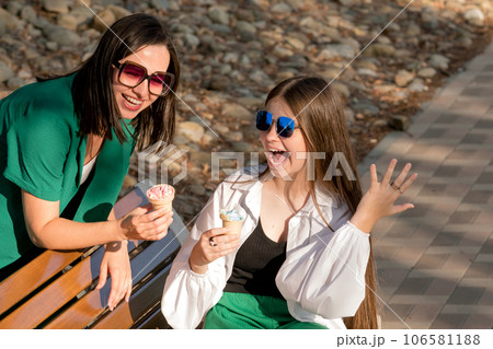 Mom and teenage daughter eat ice cream on walk Mom and teenage daughter eat ice cream on walk 106581188