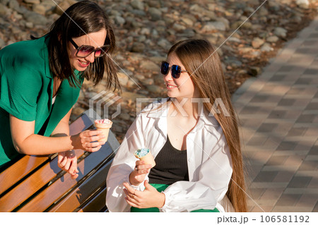 Mom and teenage daughter eat ice cream on walk 106581192