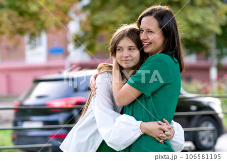 Mom and teenage daughter hugging on walk in park 106581195