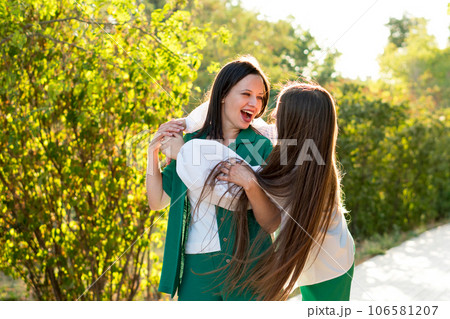 Mom and teenage daughter hugging on walk in park Mom and teenage daughter hugging on walk in park 106581207