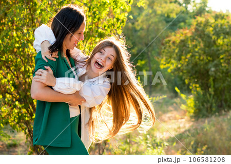 Mom and teenage daughter hugging on walk in park 106581208