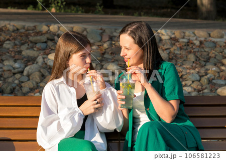 Mom and teenage daughter drink soft drinks on walk Mom and teenage daughter drink soft drinks on walk 106581223