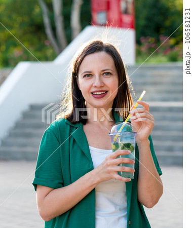 Woman drink soft drink on walk in park Woman drink soft drink on walk in park 106581231