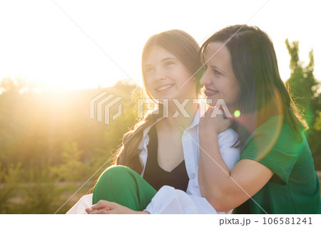 Mom and teenage daughter hugging on walk in park 106581241