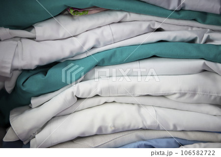 White and green medical gowns are stacked. 106582722