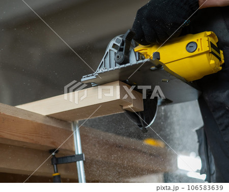 Master cuts the board with a circular saw in the workshop. Close-up of a carpenter's hands at work.  106583639