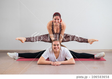 Caucasian woman doing a handstand on her friend. Pair acrobatics. Caucasian woman doing a handstand on her friend. Pair acrobatics. 106583658