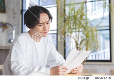 書類を見て悩む男性 106584210