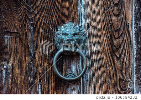 Old-fashioned door knocker in shape of a lion head somewhere on a door in downtown Matera, Southern Italy 106584232