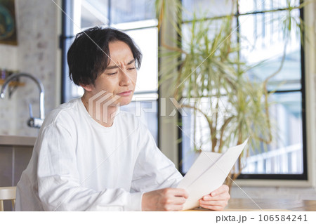 書類を見て悩む男性 106584241