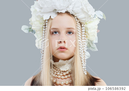 Attractive young girl in pearls and white flower hat on grey background 106586392