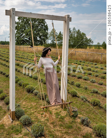 Beautiful young caucasian woman swinging on a wooden swing. 106586425