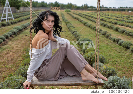Beautiful young caucasian woman sitting on a wooden swing. 106586426
