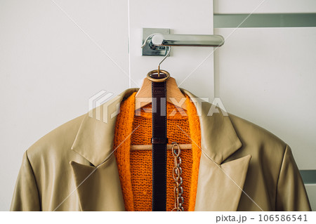 Capsule Wardrobe Autumn 2023, What To Wear This Fall. Autumn fall minimalist wardrobe with orange warm knitted sweater on wooden clothes hanger. Autumn capsule, warm fashion trends Capsule Wardrobe Autumn 2023, What To Wear This Fall. Autumn fall minimalist wardrobe with orange warm knitted sweater on wooden clothes hanger. Autumn capsule, warm fashion trends 106586541