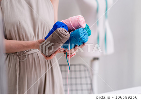 Fashion designer holds pile of macrame yarn coils in fashion studio woman dressmaker shows threads bobbins for macrame craft in sewing workshop closeup Fashion designer holds pile of macrame yarn coils in fashion studio woman dressmaker shows threads bobbins for macrame craft in sewing workshop closeup 106589256