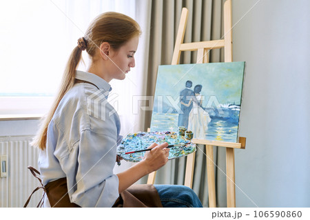 Young pretty female artist painting with acrylics on an easel 106590860