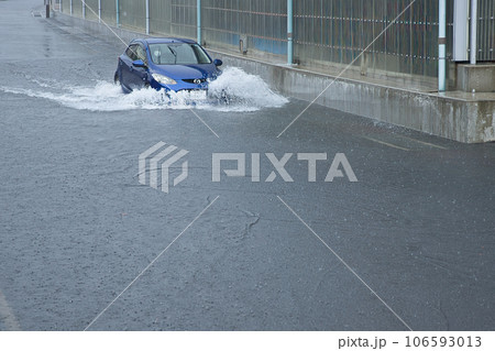 豪雨で冠水した道路を走る車 106593013