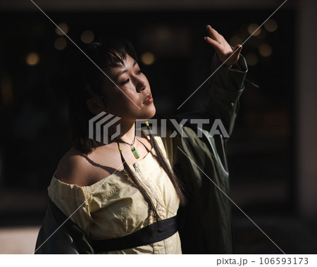Portrait of a young Asian woman in a green leather coat on a walk. Girl enjoying the sun. Portrait of a young Asian woman in a green leather coat on a walk. Girl enjoying the sun. 106593173