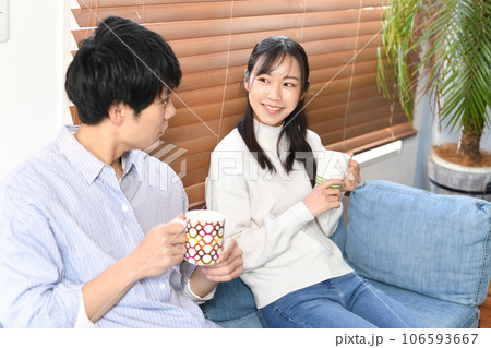 屋内でカップを持ち会話する若いカップル 106593667