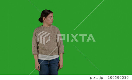 Front view of person showing refusal and pushing thing aside, expressing rejection and denial looking discontent. Female model acting displeased moving object, standing over greenscreen. 106596056