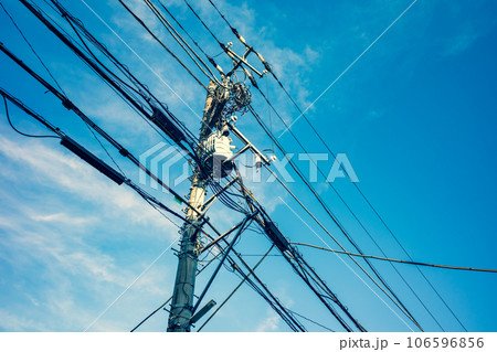 青空の下の電信柱と電線 入り組む各種のケーブル　暖色寒色強調 106596856