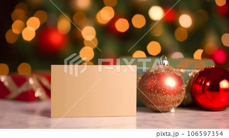 Mockup blank gold paper note greeting card, space for text with red baubles and gift box on blurry Christmas tree background, Chirstmas background. Generative AI 106597354