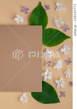 Composition with empty envelope and beautiful spring lilac flowers on beige background. Mockup card invitation greeting card postcard copy space template. Branches of lilac blooming bouquet.  106597771