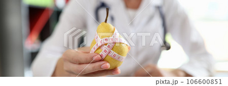 Doctor nutritionist holding ripe yellow pear with measuring tape 106600851