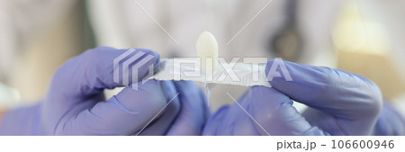 Doctor hands in gloves holding opened suppositories for anal or vaginal use 106600946