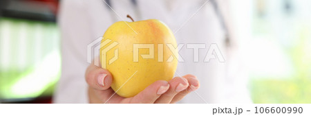 Doctor nutritionist holding ripe yellow apple in hand Doctor nutritionist holding ripe yellow apple in hand 106600990