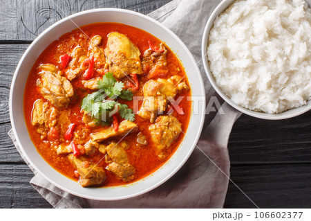 Asian chicken curry in a sauce consisting of onion, ginger, lemongrass, pepper, garlic and tomato close-up in a bowl. Horizontal top view Asian chicken curry in a sauce consisting of onion, ginger, lemongrass, pepper, garlic and tomato close-up in a bowl. Horizontal top view 106602377