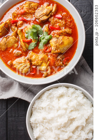 Burmese Chicken Curry has an abundance of colour, fragrance and flavour served with rice closeup on the wooden table. Vertical top view Burmese Chicken Curry has an abundance of colour, fragrance and flavour served with rice closeup on the wooden table. Vertical top view 106602383