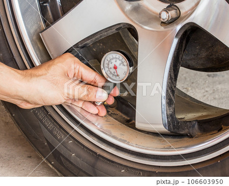 Hand holding pressure gauge for car tyre pressure Hand holding pressure gauge for car tyre pressure 106603950