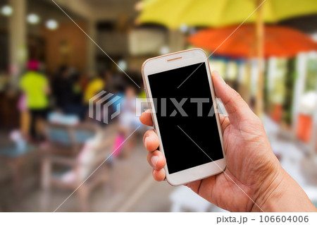 Hand holding smart phone with blur background Hand holding smart phone with blur background 106604006