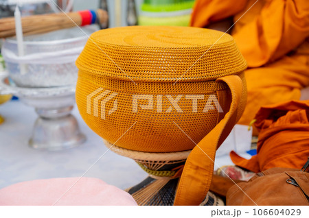 A metal alms bowl covered with golden-orange cloth to receive food from laypeople and people who believe in Buddhism. 106604029