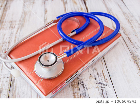 Stethoscope on book on wooden table 106604543