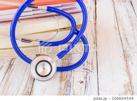 Stethoscope and book on white wooden table 106604544
