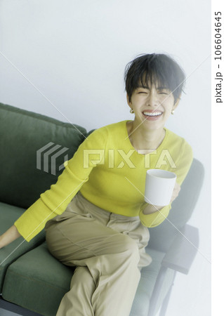 白背景のグリーンのソファに座る黄色い服を着た若い女性のファッションポートレート 縦位置 白背景のグリーンのソファに座る黄色い服を着た若い女性のファッションポートレート 縦位置 106604645
