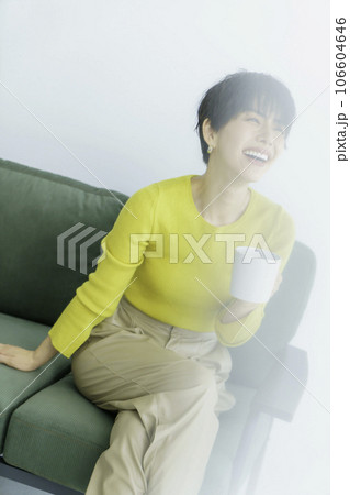 白背景のグリーンのソファに座る黄色い服を着た若い女性のファッションポートレート 縦位置 白背景のグリーンのソファに座る黄色い服を着た若い女性のファッションポートレート 縦位置 106604646