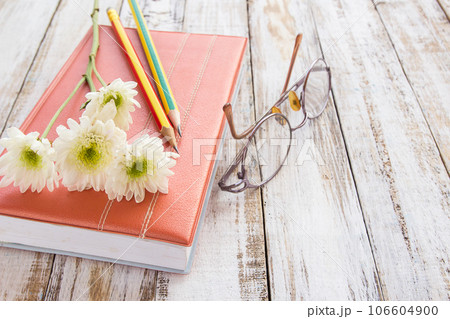 White flower and pencil on notebook on wooden table White flower and pencil on notebook on wooden table 106604900