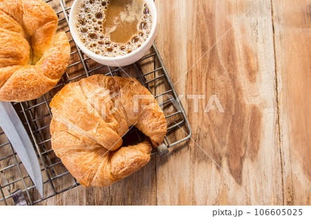 Croissant and coffee for breakfast on old wooden table 106605025