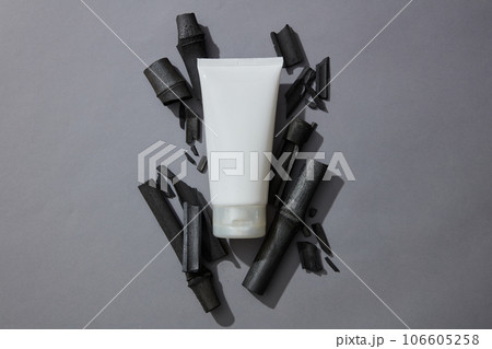 Empty label tube in white color placed on a pile of activated charcoal sticks. Activated bamboo charcoal help the body can excrete toxins out to purify and detoxify the body 106605258