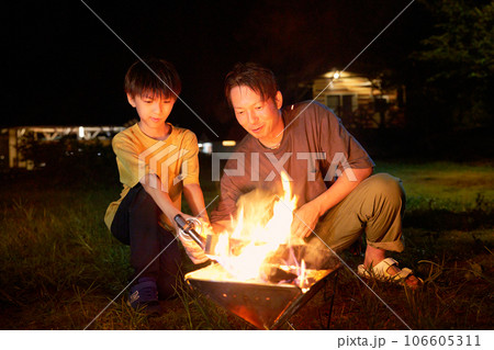 焚き火を楽しむ息子と父親 ファミリーキャンプ イメージ 焚き火を楽しむ息子と父親 ファミリーキャンプ イメージ 106605311