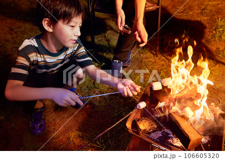 焚き火でマシュマロを炙る小学生の男の子　ファミリーキャンプ　イメージ 106605320