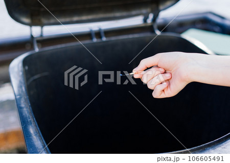 Separate waste collection, hand with matches close to dumpster trash can 106605491