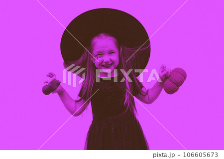 Tinted image. Portrait of a little girl in a witch costume with a spider web pattern on his face and a pumpkin in his hands. 106605673