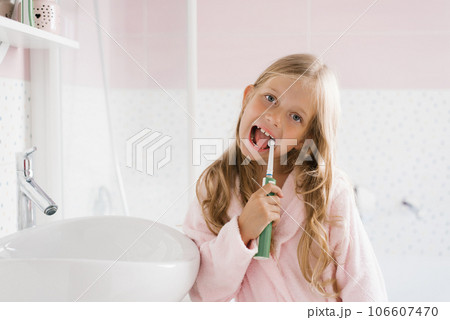 Child brushes his teeth in the bathroom in the morning after sleeping. A girl with toothpaste and a brush. Dental and oral hygiene, care. 106607470