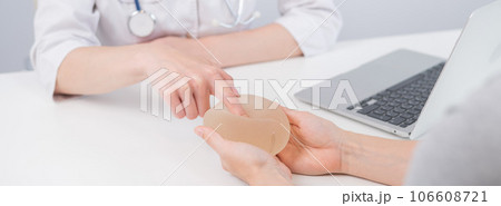 Caucasian woman and plastic surgeon touching and choosing breast implants.  106608721