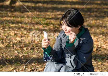 拾ったドングリを撮影する女性 106609952