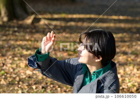 ドングリを手に持つ女性 106610050